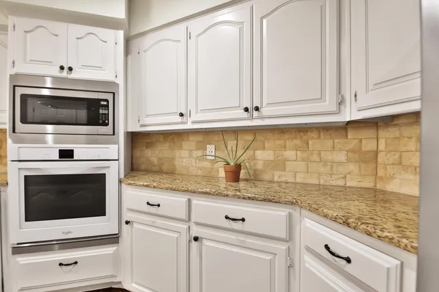 a kitchen with granite countertop white cabinets stainless steel appliances and a sink
