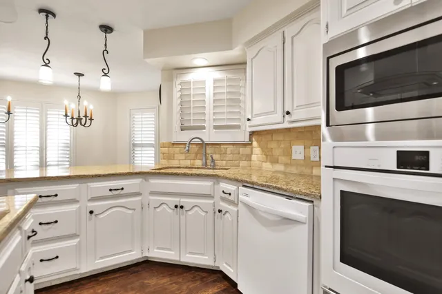 a kitchen with granite countertop white cabinets white appliances and a sink