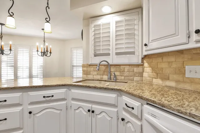 a kitchen with granite countertop a sink window and cabinets