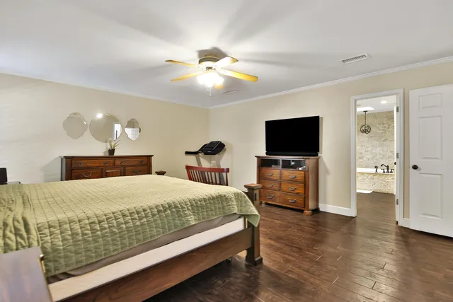 a bedroom with a bed and a flat tv screen on dresser
