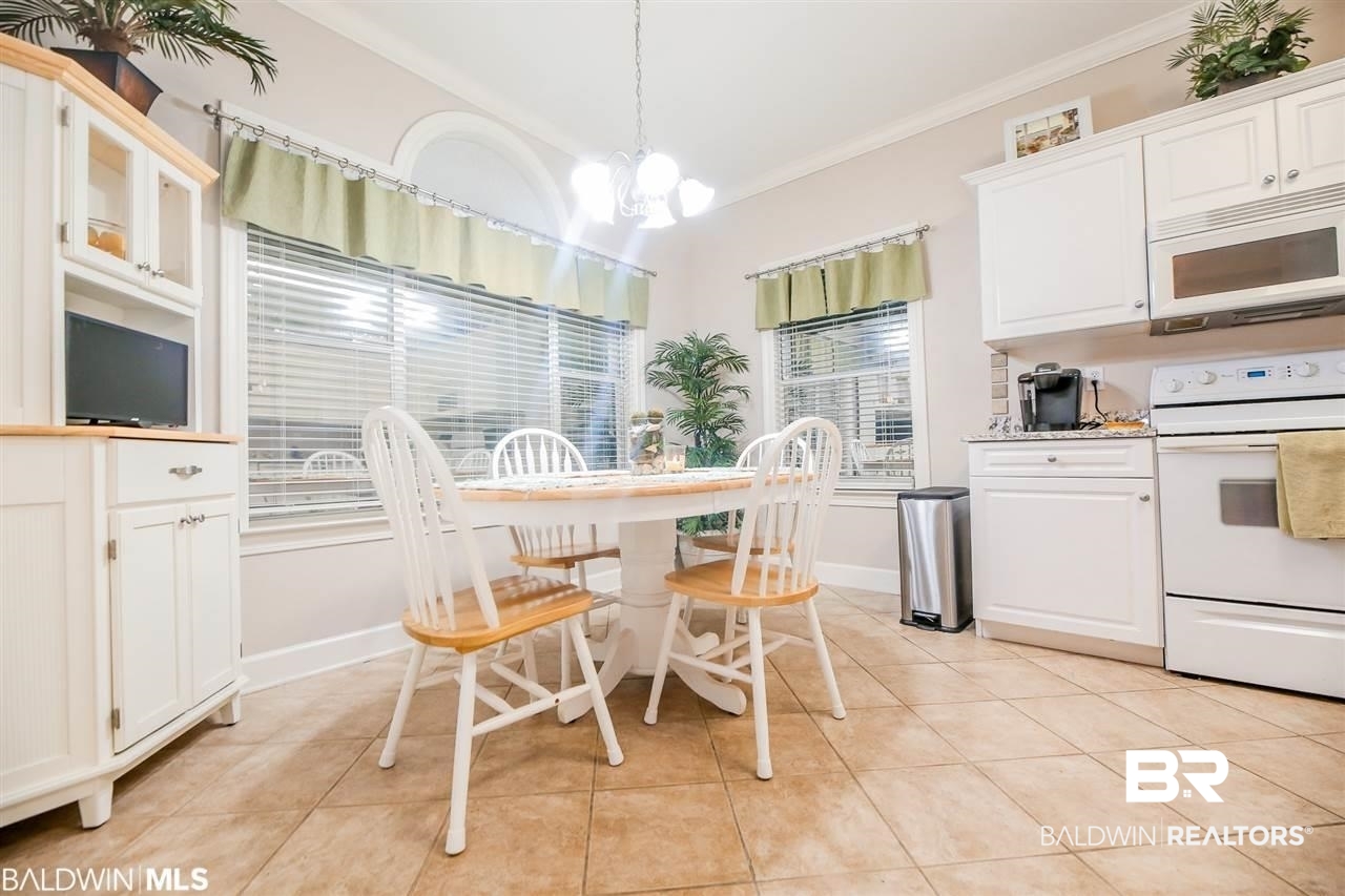 Kitchen with ornamental molding, white cabinetry, decorative light fixtures, and white appliances