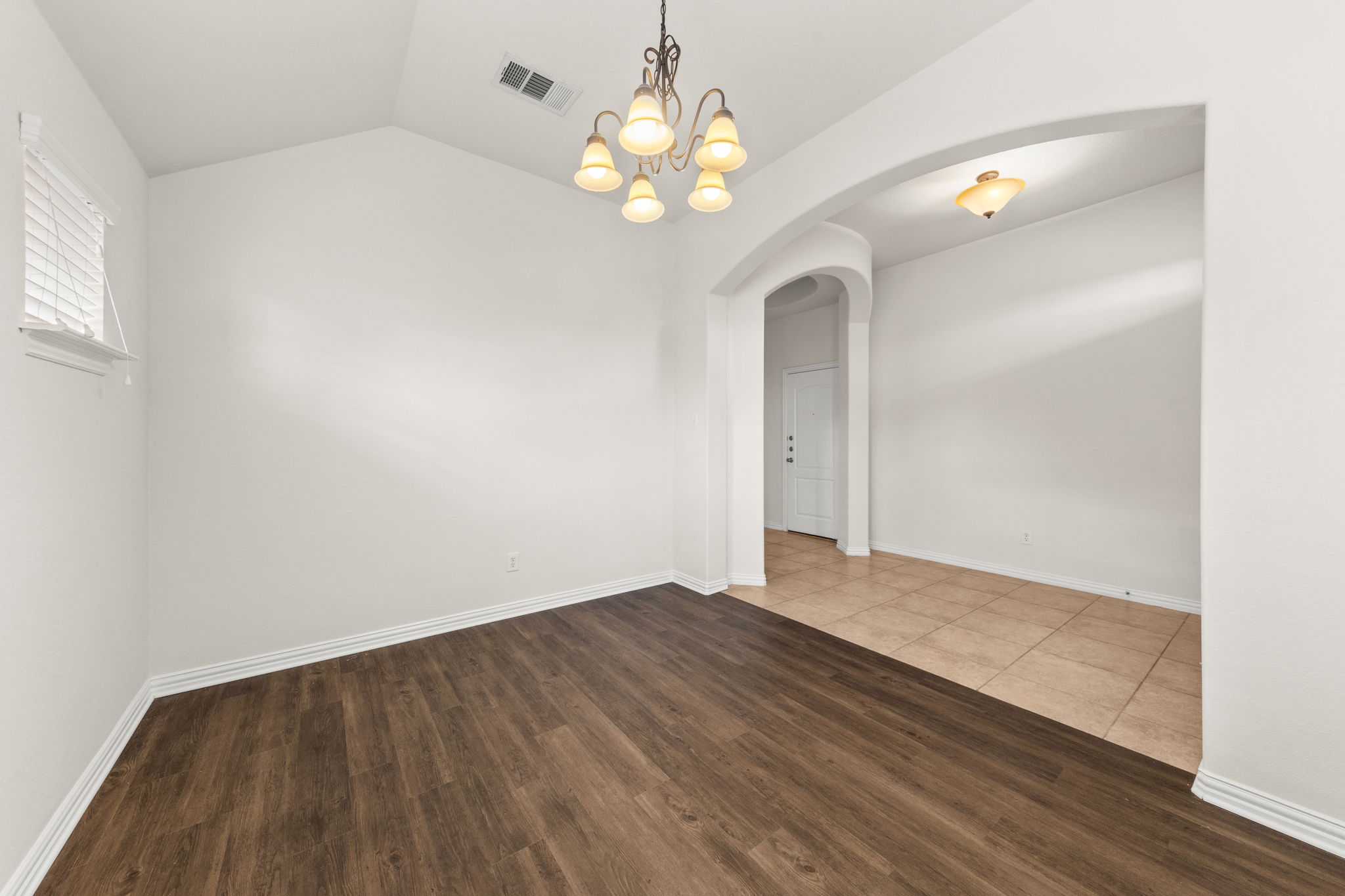 411 Tascate Street Georgetown, TX 78628 - Photo 5 of 41 A traditional chandelier illuminates this inviting dining area, showcasing rich hardwood and tile flooring.
