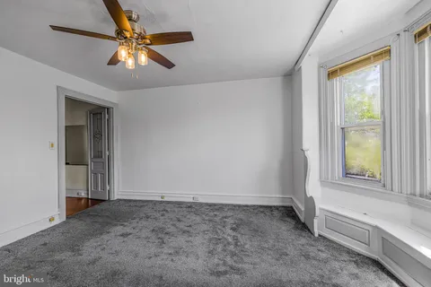an empty room with a window and a chandelier fan