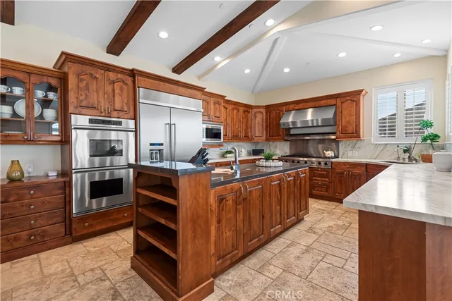 a kitchen with stainless steel appliances kitchen island granite countertop a stove a sink and a refrigerator