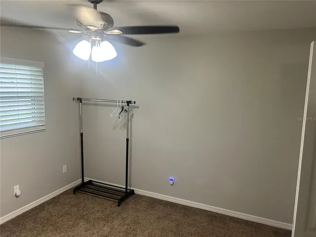 an empty room with a chandelier fan and a window