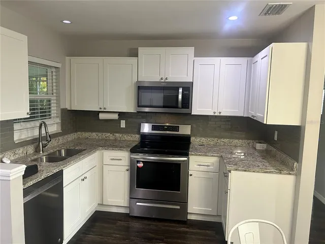 a kitchen with granite countertop a stove a sink and a microwave