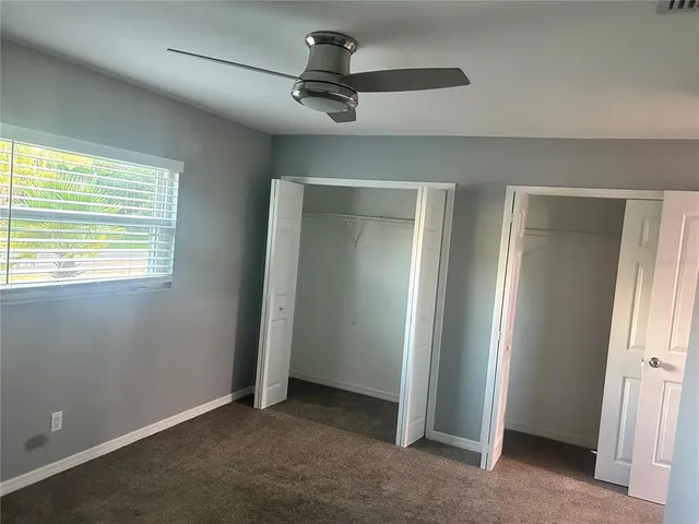an empty room with a ceiling fan and window