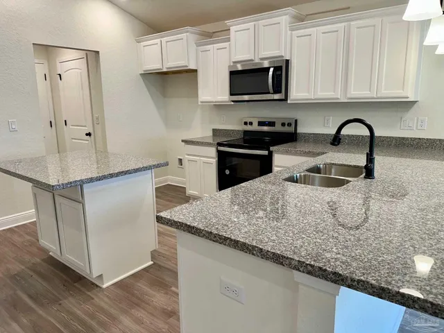 a kitchen with stainless steel appliances granite countertop a sink a stove and microwave