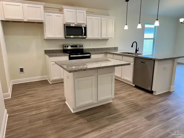 a kitchen with stainless steel appliances granite countertop a sink a stove a microwave and wooden cabinets