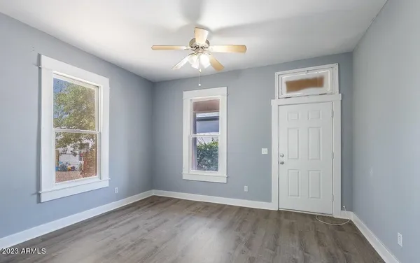 a view of an empty room with wooden floor and a window