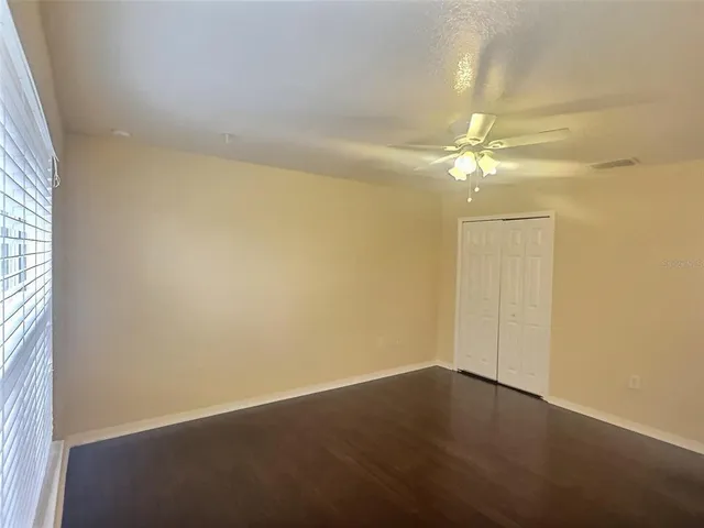 an empty room with a chandelier fan and windows