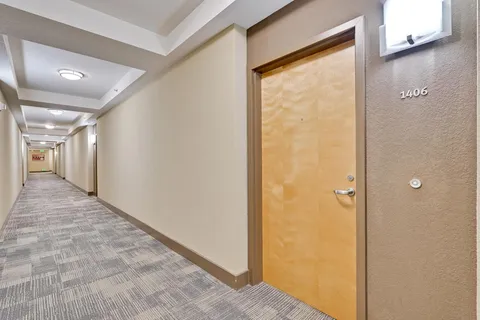 a view of a hallway with wooden floor and a bathroom