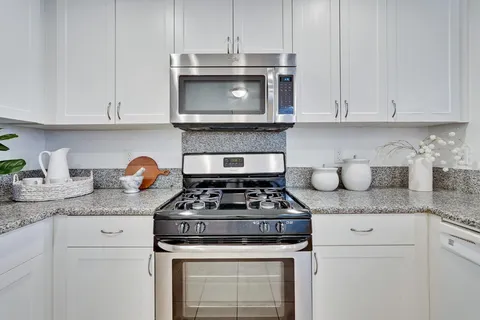 a kitchen with granite countertop white cabinets and stainless steel appliances