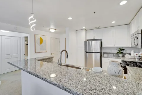 a kitchen with stainless steel appliances granite countertop a sink a refrigerator and a granite counter tops