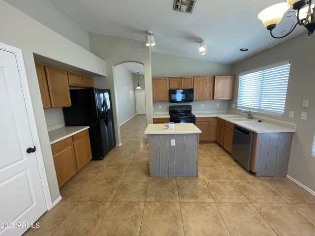 a room with kitchen island stainless steel appliances a couch wooden floor and cabinets