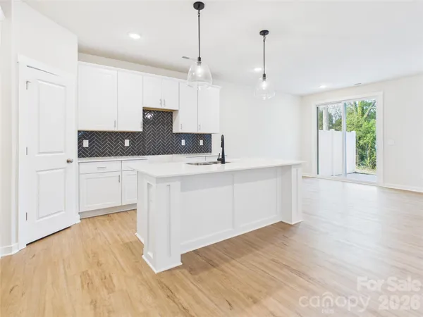 a kitchen with stainless steel appliances granite countertop a refrigerator a stove a sink dishwasher and white cabinets with wooden floor