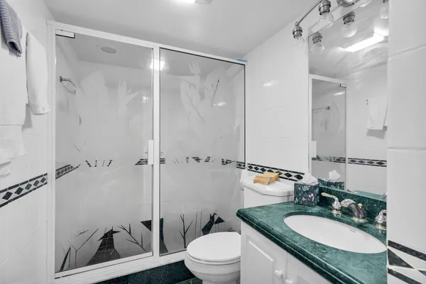 a bedroom with a bed a mirror on dresser and next to a window