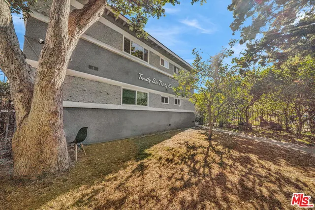 a backyard of a house with large trees and outdoor seating
