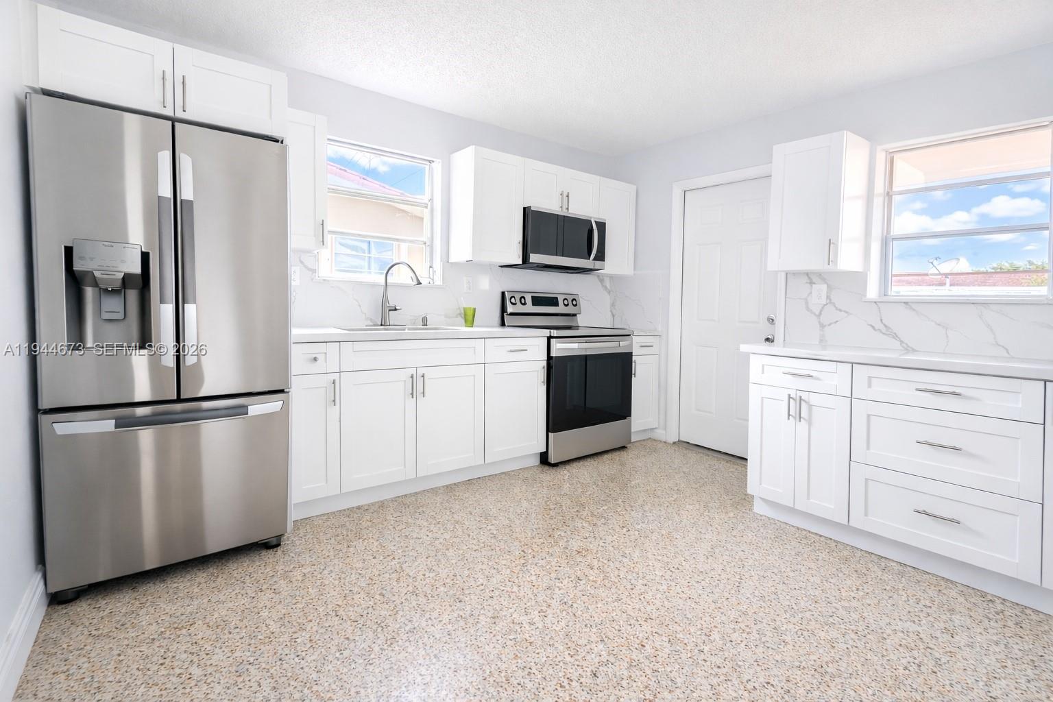 11333 Southwest 7th Terrace Sweetwater, FL 33174 - Photo 4 of 13 a kitchen with stainless steel appliances white cabinets and a refrigerator