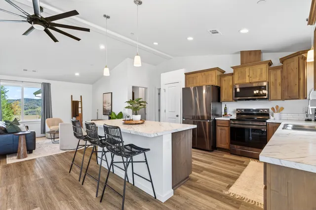 a kitchen with stainless steel appliances kitchen island granite countertop a refrigerator a stove top oven a sink dishwasher a dining table and chairs with wooden floor