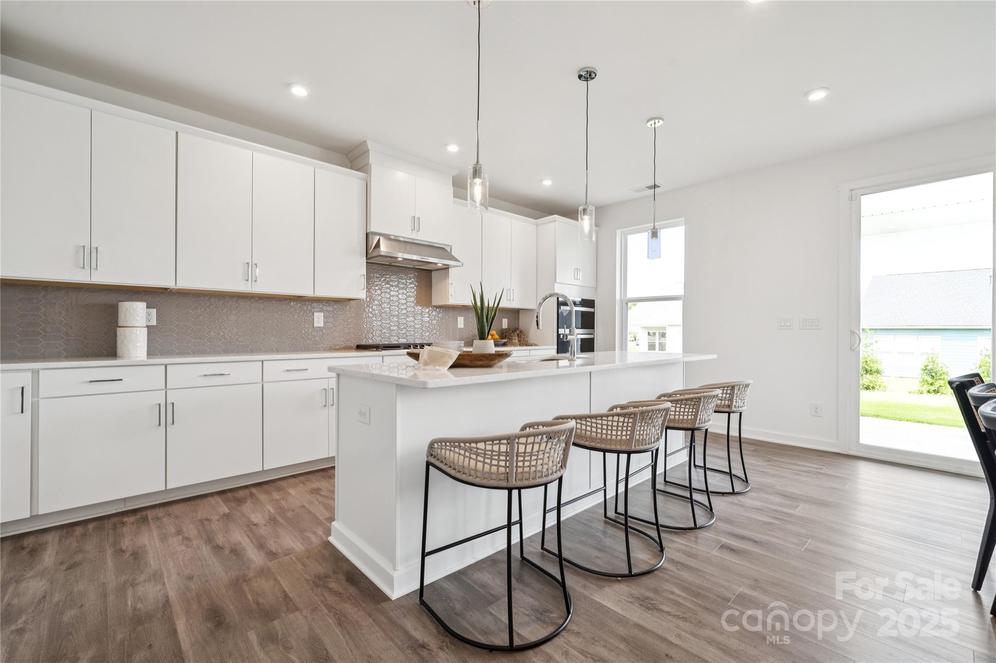 5259 Vernon Rdg Road, Unit 76 Huntersville, NC 28078 - Photo 7 of 14 a kitchen with stainless steel appliances granite countertop white cabinets a sink a stove a dining table and chairs with wooden floor