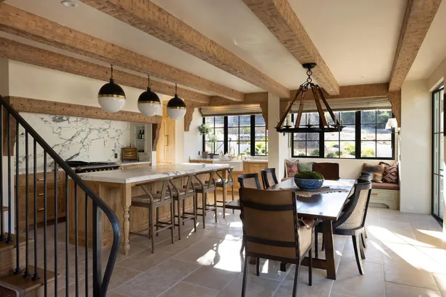 a dining hall with stainless steel appliances kitchen island granite countertop a table and chairs in it