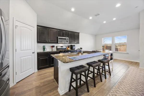 a kitchen with stainless steel appliances granite countertop a stove a sink a refrigerator a microwave and cabinets