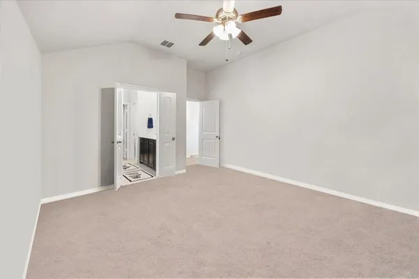 an empty room with fireplace and a ceiling fan