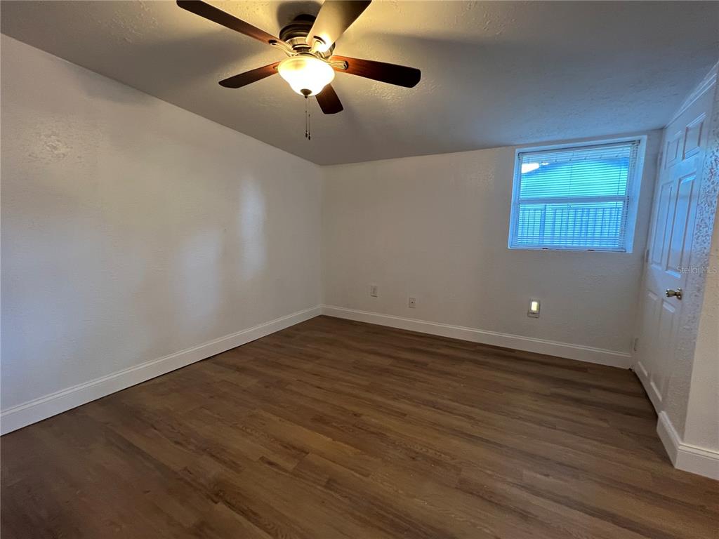 2120 10th Street St. Cloud, FL 34769 - Photo 5 of 8 an empty room with wooden floor chandelier fan and windows