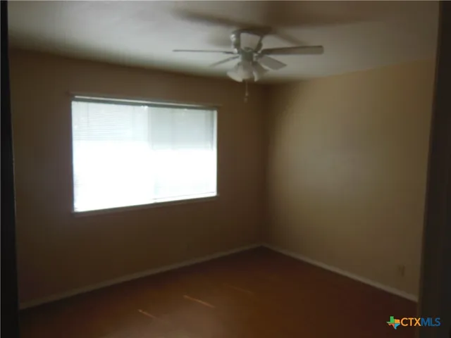 a view of room with window ceiling fan and hardwood floor