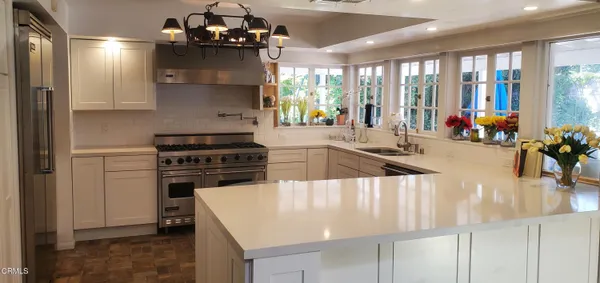 a kitchen with a stove a chandelier and living room view
