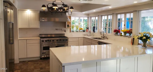 a kitchen with a stove a chandelier and living room view