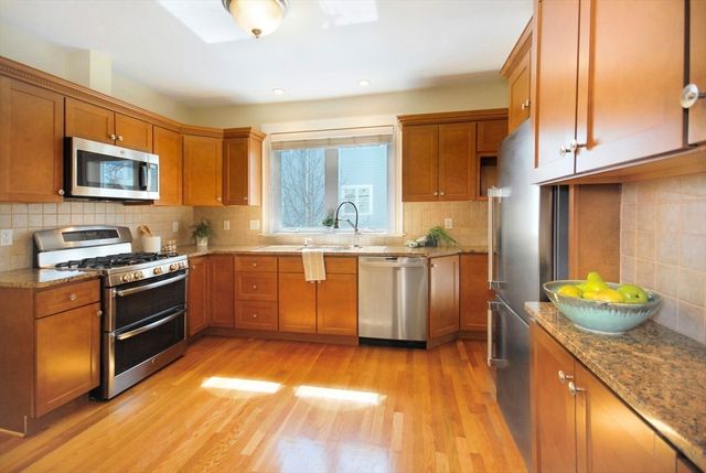 a kitchen with stainless steel appliances granite countertop a stove a sink and a refrigerator