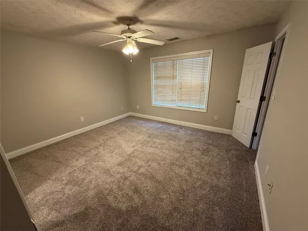 an empty room with windows and fan