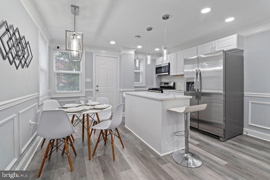 300 Denison Street Baltimore, MD 21229 - Photo 9 of 25 a kitchen with a table chairs refrigerator and microwave