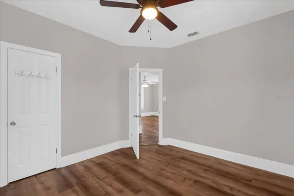 a view of empty room with wooden floor and ceiling fan