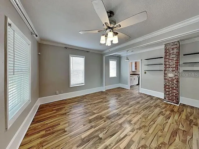 a view of empty room with wooden floor and fan