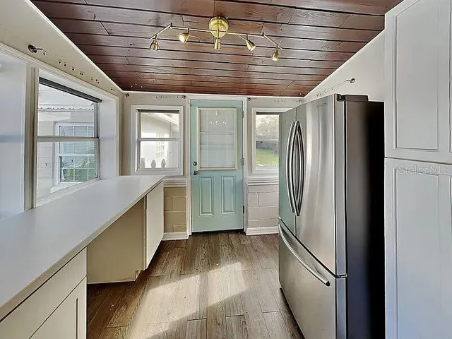 a view of a kitchen with a refrigerator and wooden floor