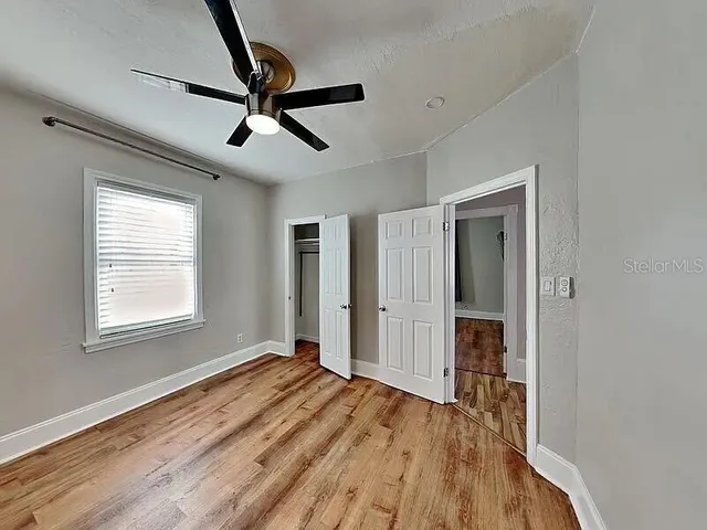a view of empty room with wooden floor and ceiling fan