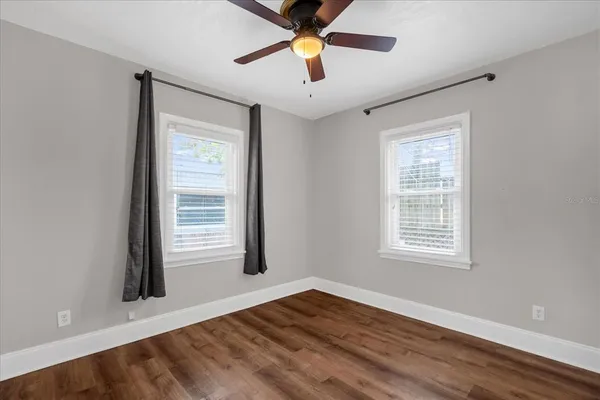a view of an empty room with window and a chandelier fan