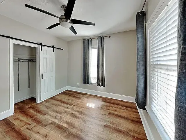a view of empty room with wooden floor and fan