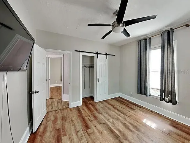 a view of empty room with wooden floor and fan