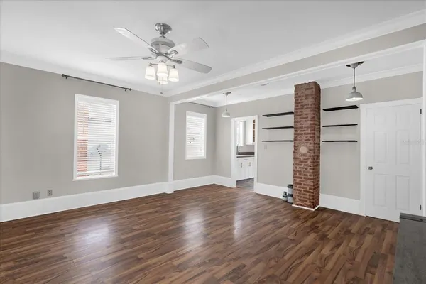 an empty room with wooden floor chandelier and windows