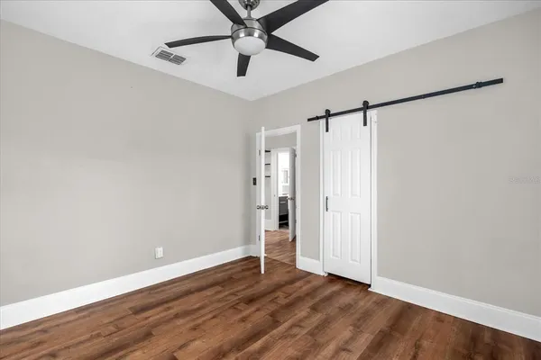 an empty room with wooden floor closet and windows