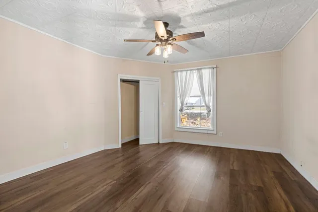 a view of an empty room with wooden floor and a window