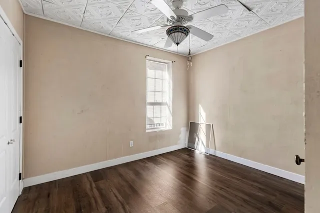 an empty room with wooden floor chandelier fan and windows