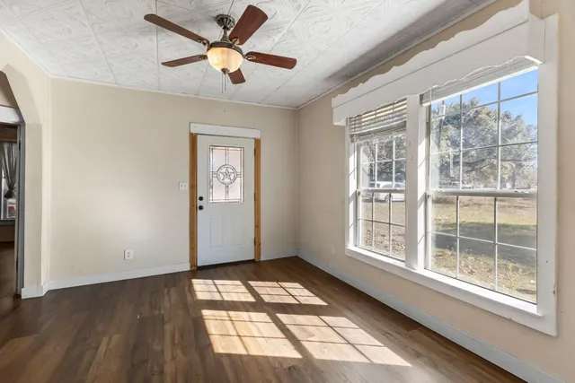 a view of an empty room with a window and wooden floor