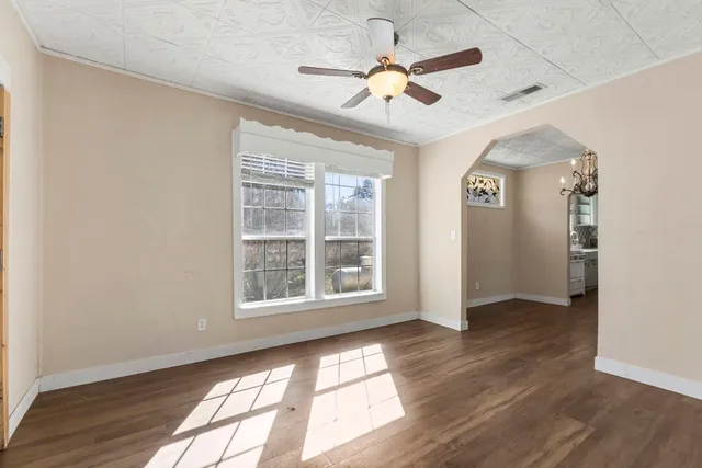 a view of an empty room with a window and wooden floor