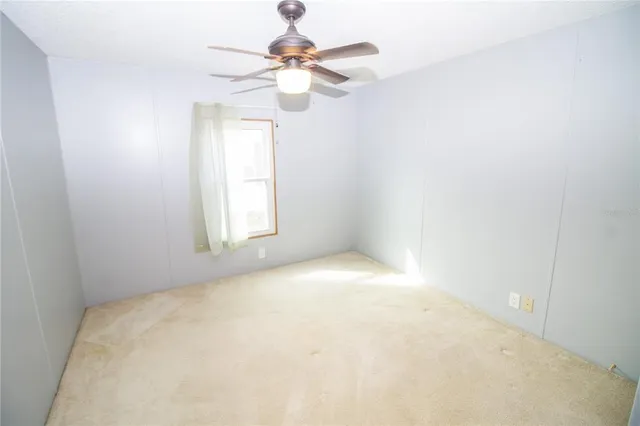an empty room with a chandelier fan and windows