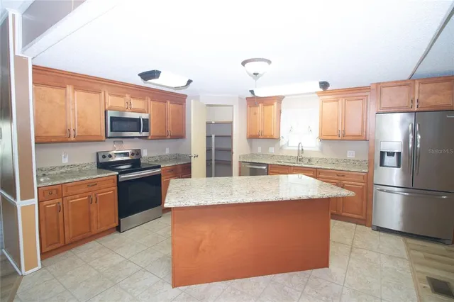 a large kitchen with granite countertop a refrigerator stove top oven and sink